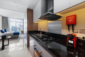 a kitchen with a stove top oven next to a living room at New Aparthotel Prive in Dubai