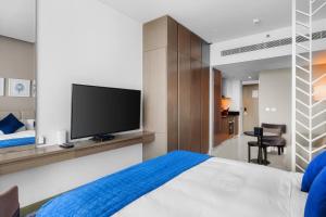 New Aparthotel Prive في دبي: غرفة نوم بسرير وتلفزيون بشاشة مسطحة