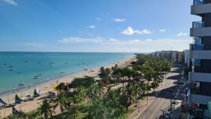 uma vista para uma praia com palmeiras e para o oceano em Apartamento Beira Mar de Pajuçara / Maceió em Maceió