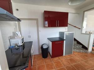 a kitchen with red cabinets and a refrigerator at Maison 6 pers proche plage de Tanchet in La Pironnière +10 photos