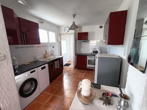 uma cozinha com armários vermelhos e uma máquina de lavar e secar roupa em Maison 6 pers proche plage de Tanchet em La Pironnière