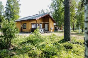 a small wooden cabin in a forest with a tree at Marjoniemi Camping in Hiidenniemi