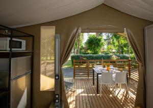 a tent with a table and chairs on a deck at Camping Le Both d'Orouet in Saint-Jean-de-Monts