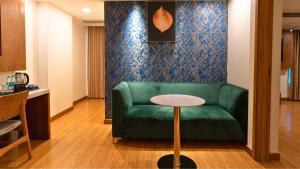 a living room with a green couch and a table at The Orion Plaza - Nehru Place in New Delhi