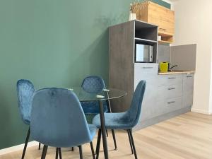 une salle à manger avec des chaises bleues et une table en verre dans l'établissement Staywell Für 4 Parking I Netflix I Kitchen, à Paderborn
