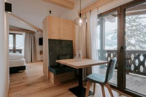 サン・ヴィジリオ・ディ・マレッベにあるGarni Residence Alnö - Adults Onlyのテーブル、椅子、ベッドが備わる客室です。