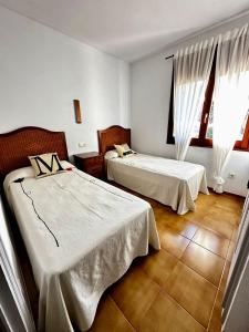 a hotel room with two beds and windows at Melis Mar - Apartamento con vistas en Pals in Pals