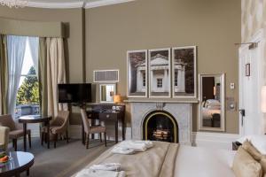 Oakley Hall Hotel في باسينغستوك: غرفة فندقية بها موقد وغرفة معيشة