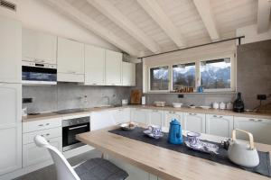 une cuisine avec des placards blancs et une table en bois dans l'établissement Residence soleluna - Loft Sirio, à Roisan
