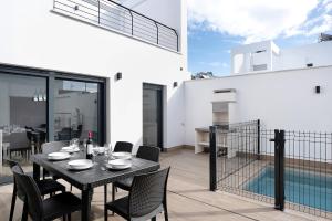 a black dining table and chairs on a balcony at Adosado Marol solo familias in Conil de la Frontera