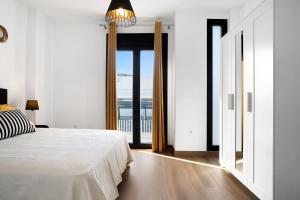 a white bedroom with a bed and a large window at Adosado Marol solo familias in Conil de la Frontera +20 photos