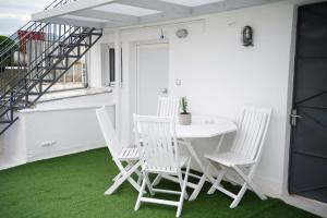 a white table and chairs on a balcony with green carpet at Central aesthetic studio with panoramic views in Patra