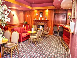 a waiting room with tables and chairs and a fireplace at George IV Hotel in Criccieth