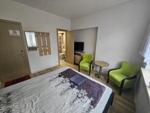 1 dormitorio con 1 cama y 2 sillas verdes en Lux kambarys centre su karališka lova #3 en Kaunas