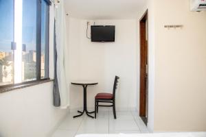 una silla y una mesa en una habitación con ventana en Trip Hotel Lauro de Freitas en Lauro de Freitas