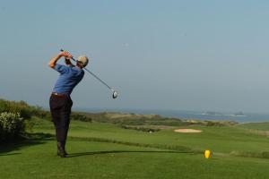 un homme balançant un club de golf sur un parcours de golf dans l'établissement No 10 The Towans, à St Merryn
