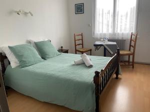 um quarto com uma cama verde com 2 cadeiras e uma mesa em L' Auberge Campagnarde, Lourdes em Poueyferré