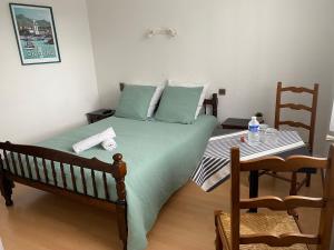 Un dormitorio con una cama verde y una mesa en L' Auberge Campagnarde, Lourdes en Poueyferré