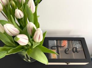 un vaso di tulipani bianchi seduto accanto a un orologio. di The blue VIEcation apartment a Vienna