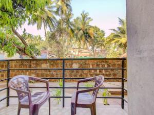 2 stoelen op een balkon met palmbomen bij zoz mg2 in Oud Goa