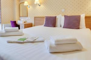 a bedroom with a large white bed with towels on it at Selborne Hotel in Dunoon