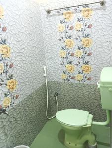 a bathroom with a toilet and flowers on the wall at Rose Villa in Puducherry