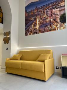 un sofá amarillo en una habitación con una pintura en la pared en MariMuntagna, en Catania