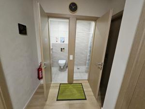 a bathroom with a toilet and a green rug at Kauno apartamentai big bed in Kaunas +10 photos