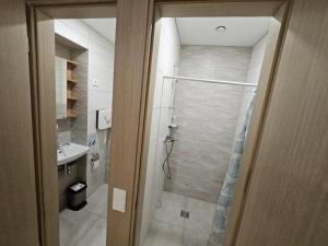 uma casa de banho com uma cabina de duche ao nível do chão ao lado de um lavatório em Centre kambarys su didele lova #1 em Kaunas