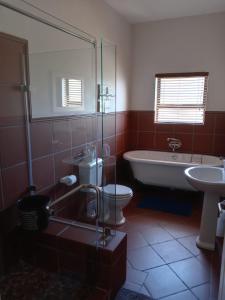 a bathroom with a tub and a toilet and a sink at LêPlek Guesthouse in Saldanha