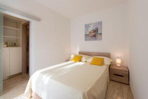 a white bedroom with a large bed with yellow pillows at HAPPY DAYS in Trogir