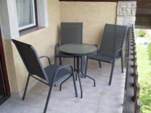 3 Stühle und ein Tisch auf einer Terrasse in der Unterkunft SZIESZTA APARTMAN in Gárdony