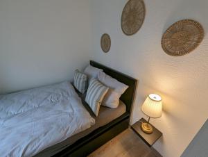 a bedroom with a bed with white sheets and a lamp at FeWo Nordstern - Schillig in Wangerland
