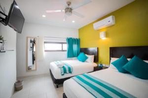 um quarto de hotel com duas camas e uma televisão em Asilé Hotel Boutique em Bacalar