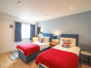 a bedroom with two beds with red and white sheets at Tradewinds Gwbert in Towyn