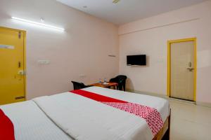 a bedroom with a bed and a table and a television at OYO Flagship Hotel VBH Inn in Kammasandra
