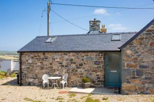 a stone building with two chairs and a table outside at The Dairy Newport, Pembrokeshire in Newport Pembrokeshire