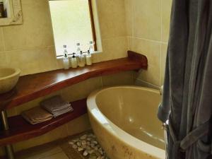 ein Badezimmer mit einer Badewanne, einem Waschbecken und einem Spiegel in der Unterkunft Waterbessiebos cottage in Tzaneen
