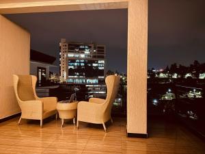 3 chaises et une table sur un balcon la nuit dans l'établissement Amora Apartment, à Kigali