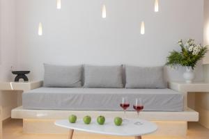 a living room with a couch and two glasses of wine at Theophrasti Suites in Foinikiá