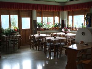 a dining room with tables and chairs and windows at Albergo Bar Ristorante Da Gina in Forni Avoltri