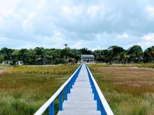 a wooden path through a marsh with a building in the background at Emerald Apartments INC in Georgetown