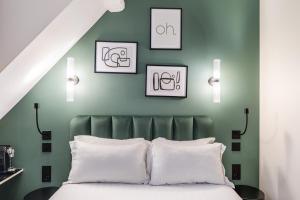 - une chambre avec des murs verts et un lit avec des oreillers blancs dans l'établissement Hotel Elysée Secret, à Paris