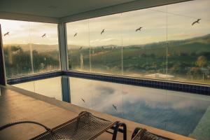 een kamer met een groot raam met vogels in de lucht bij Escarpas resort in Capitólio