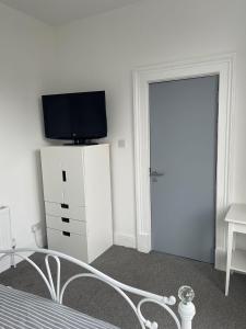 a bedroom with a bed and a tv and a door at Rock Lane Rooms in Birkenhead