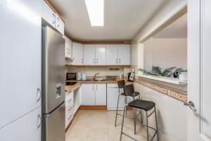 cocina con armarios blancos y nevera de acero inoxidable en Benalmádena Marina Golf Appartement - Casa Valk, en Benalmádena