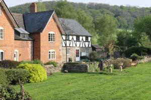 赫里福德的住宿－Dee's Cottage at Brinsop，一座古老的砖房,前面有一个花园