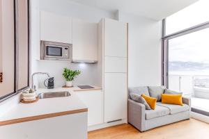 a kitchen and living room with a couch and a window at Les Appartements de Grenoble in Grenoble