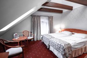 a hotel room with a bed and a table and chairs at Hotel Restauracja Browar Lwów w Lublinie in Lublin