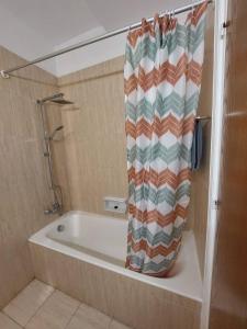 a bath tub with a shower curtain in a bathroom at Sunny 2 Bedroom Larnaca Center in Larnaca